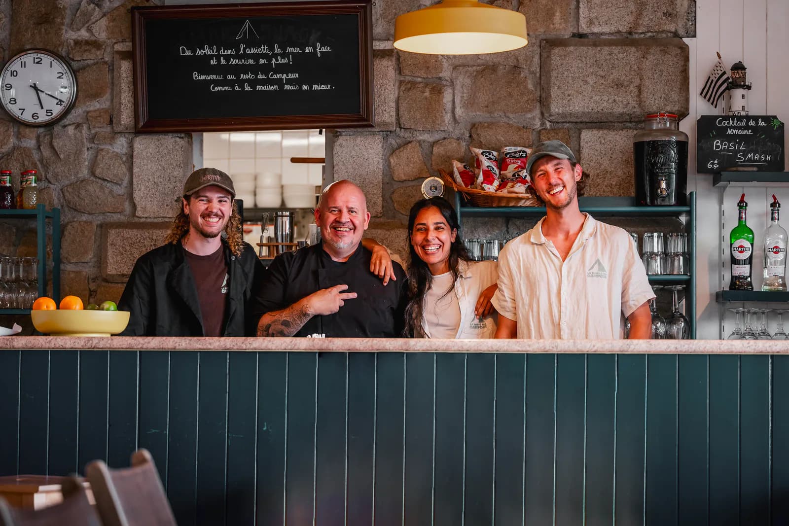 L'équipe, tout sourire, derrière le comptoir du restaurant