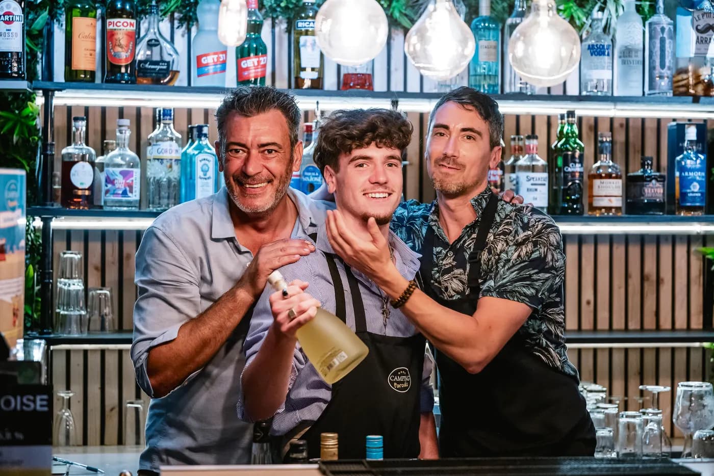 Trois membres de l'équipe, tout sourire, derrière le bar