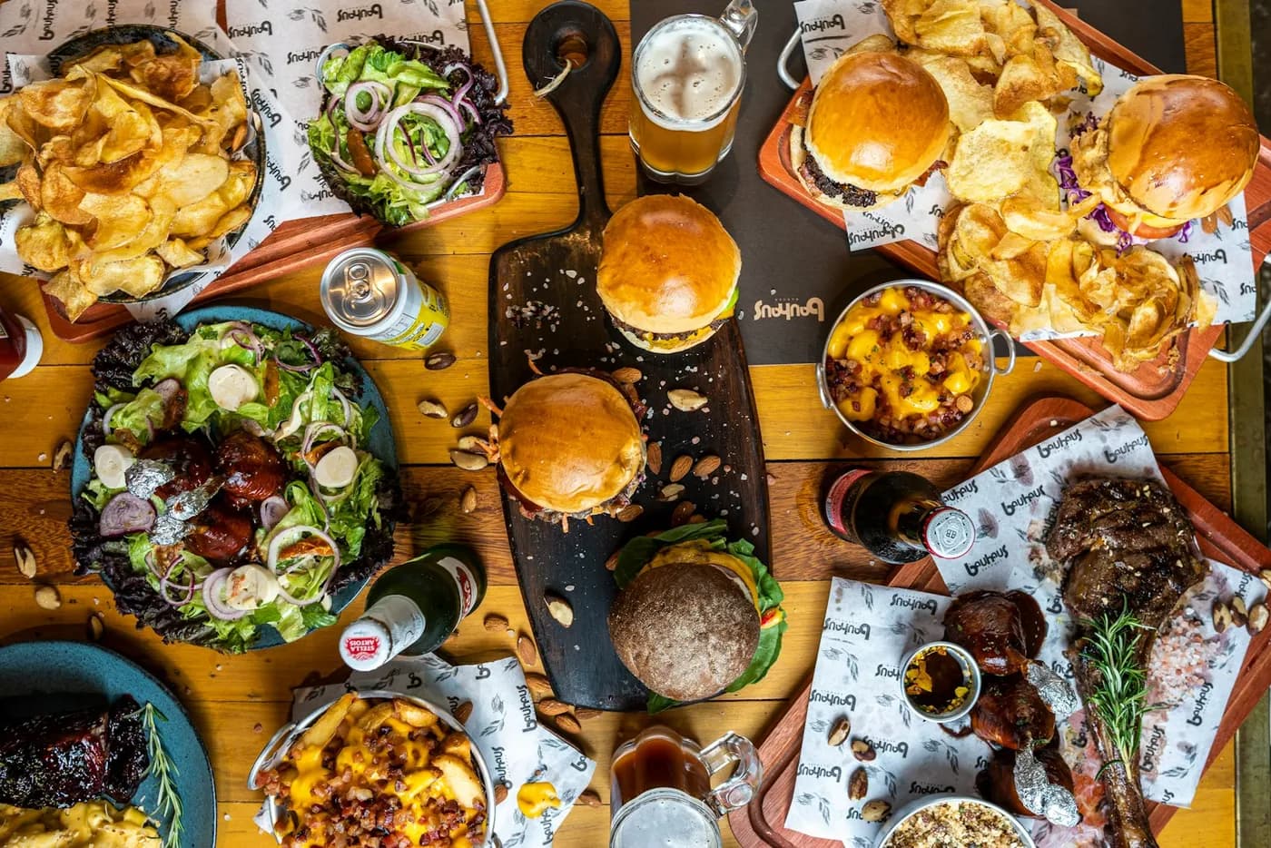 Table garnie de burgers, frites, salades et boissons à partager