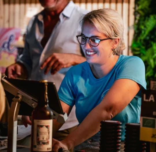 Une gérante souriante au comptoir de son restaurant