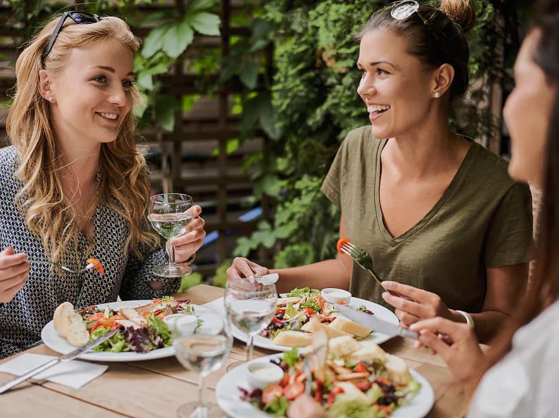 Trois amies partagent un repas en terrasse